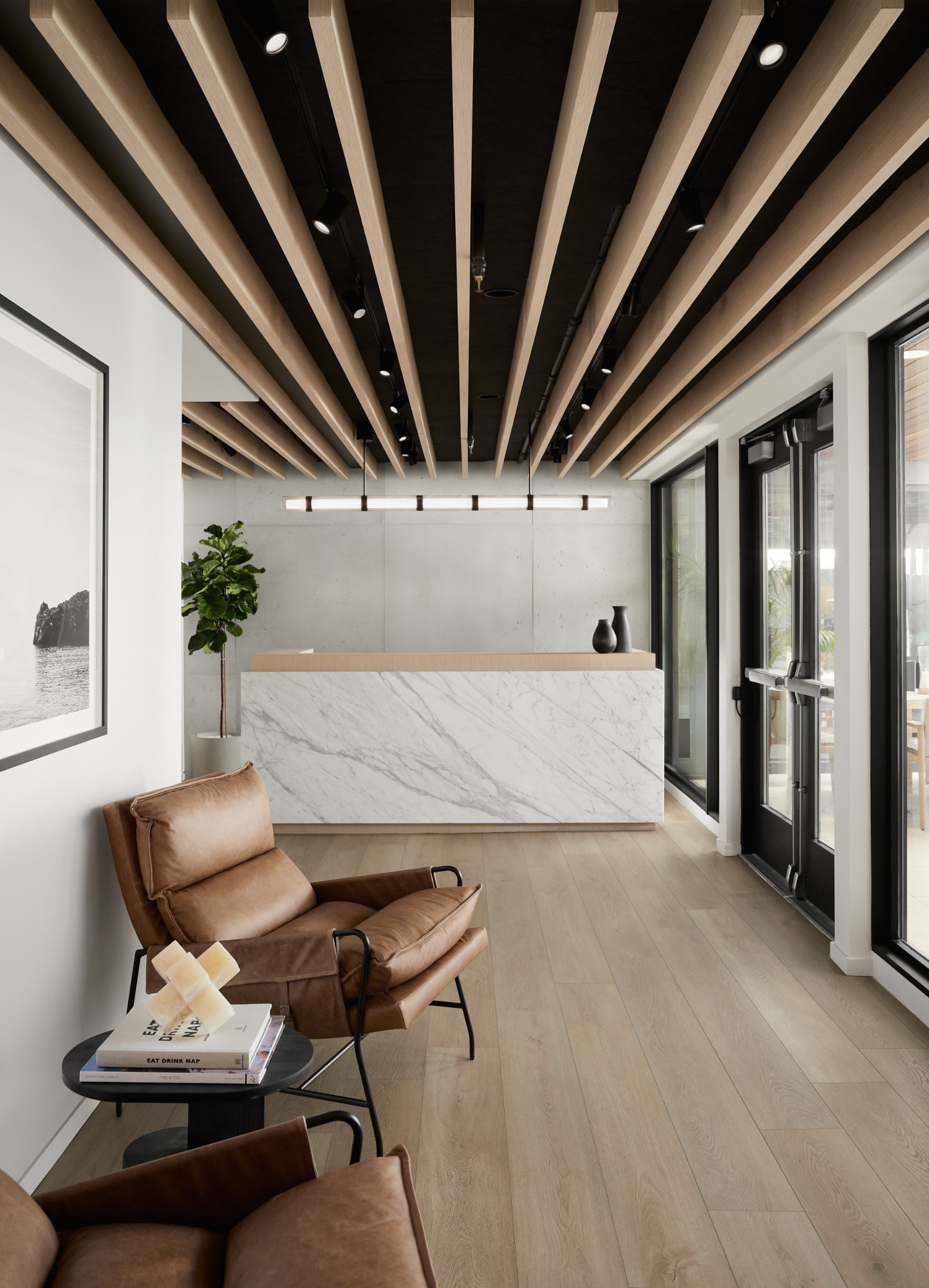 Reception lobby with a slatted wood ceiling, a marble front desk and leather armchairs