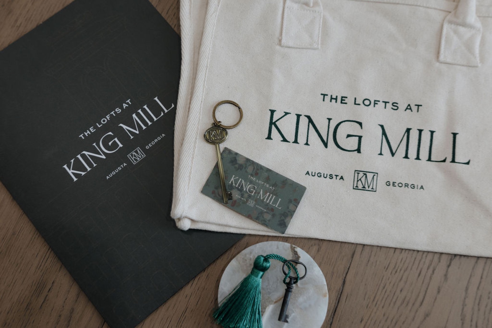A King Mill welcome kit with a branded folder, canvas tote, brass key, and key card