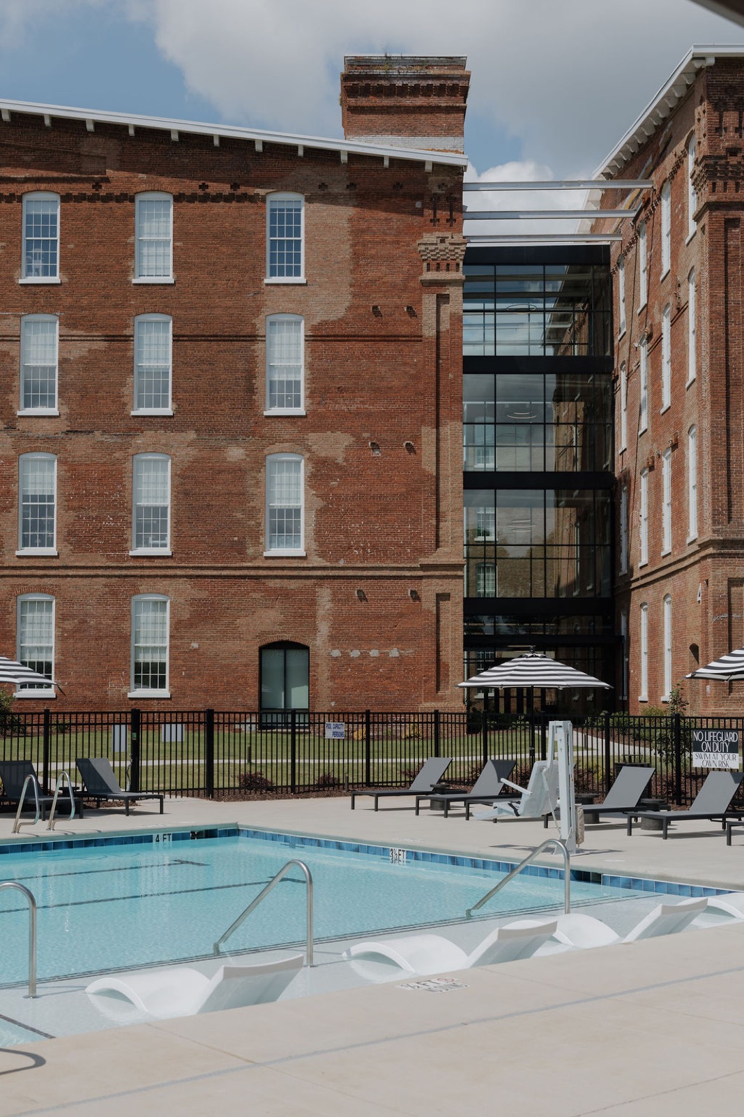 The pool in front of the brick mill with a glass-walled connector between buildings