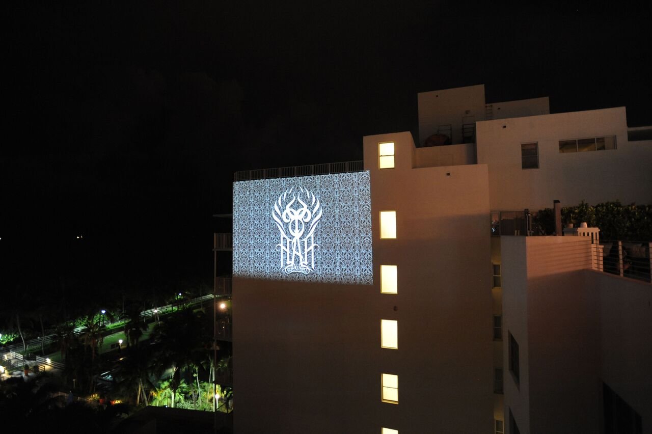 The HAH crest and a patterned design projected onto the side of a neighboring building at night
