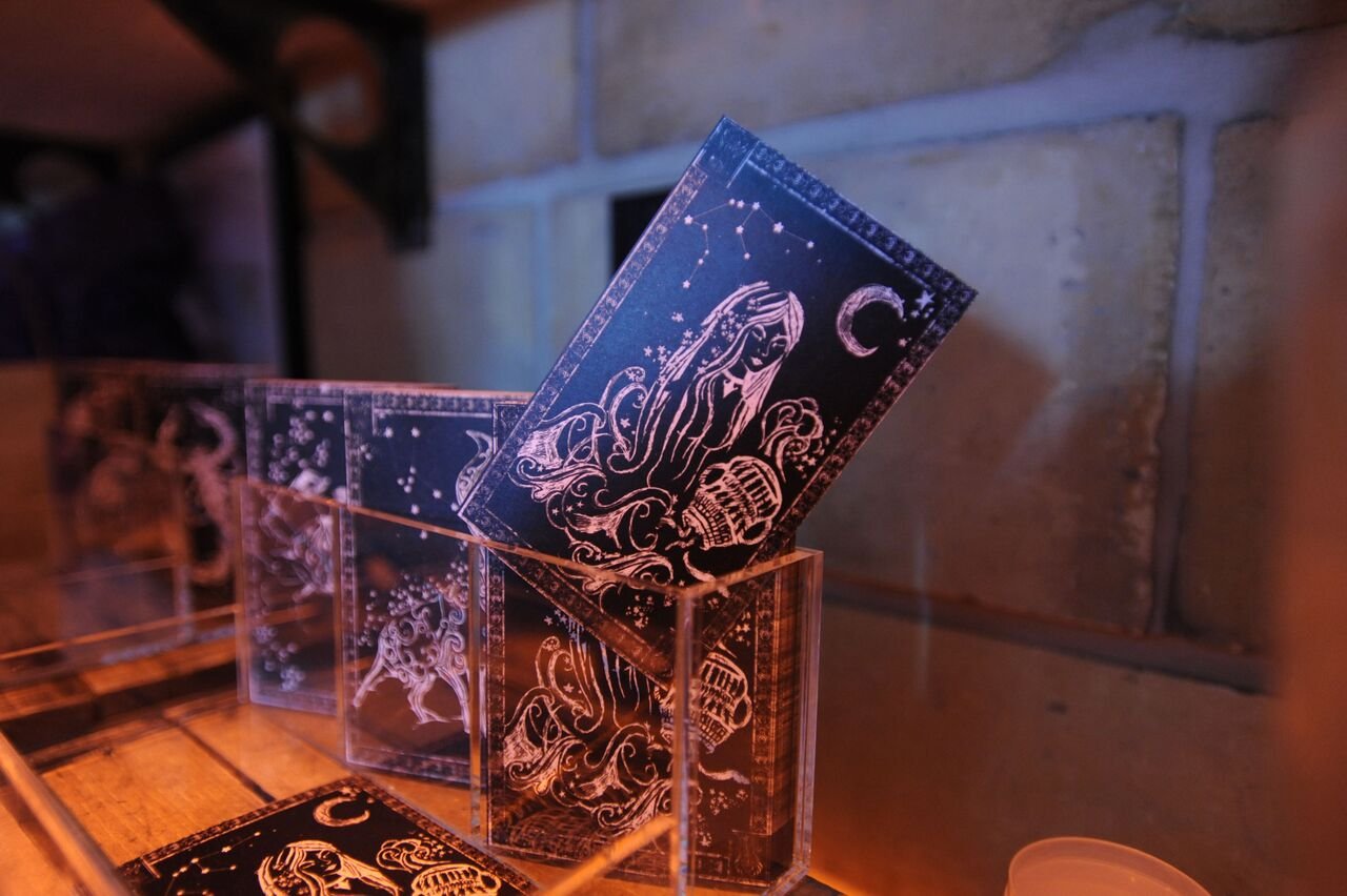 Black cards with white illustrations of constellations and figures standing in clear acrylic holders