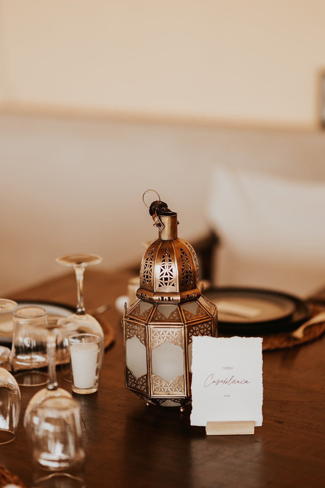 A brass and frosted-glass lantern beside a handwritten table card on a wood table