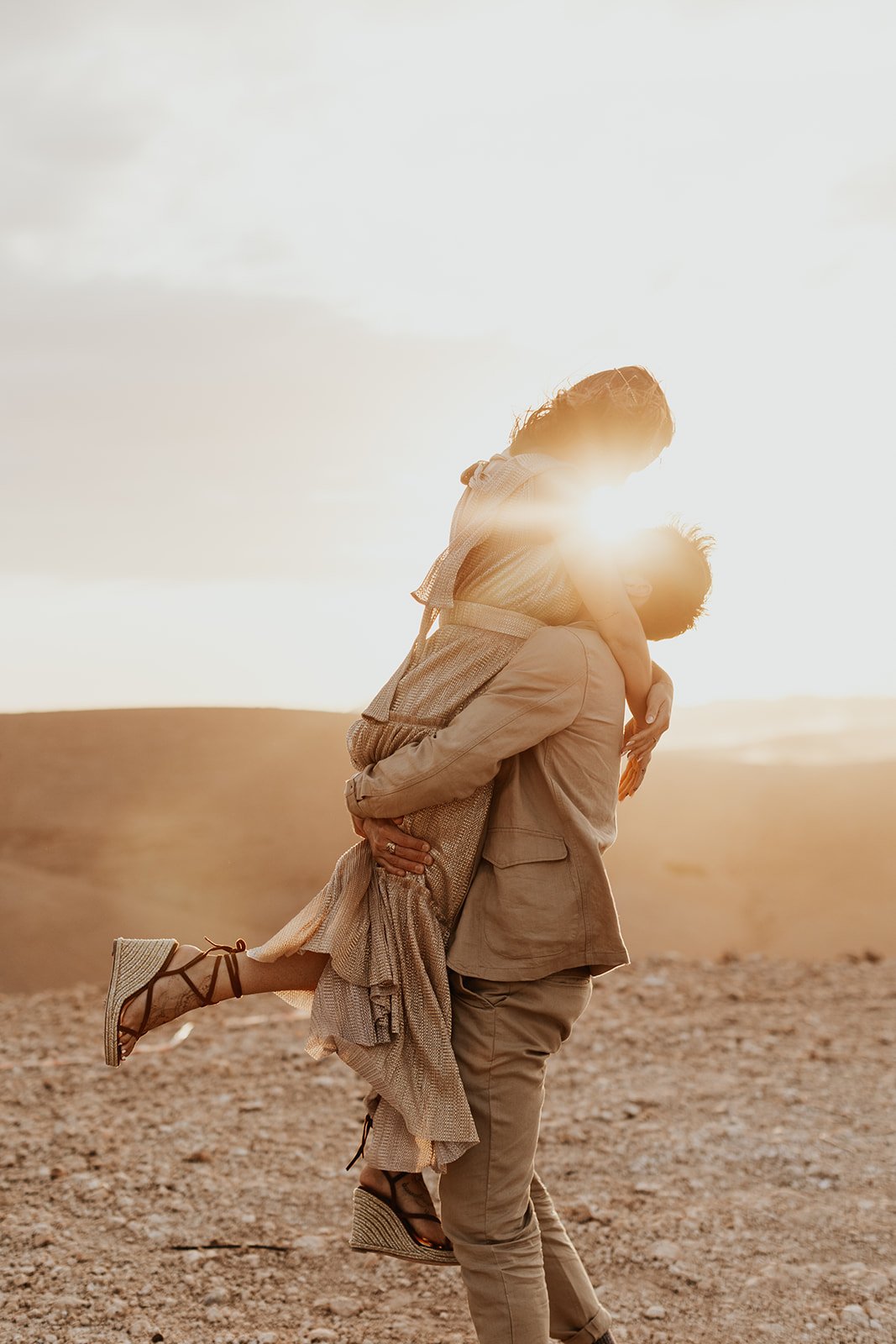 The couple embracing at sunset in the desert