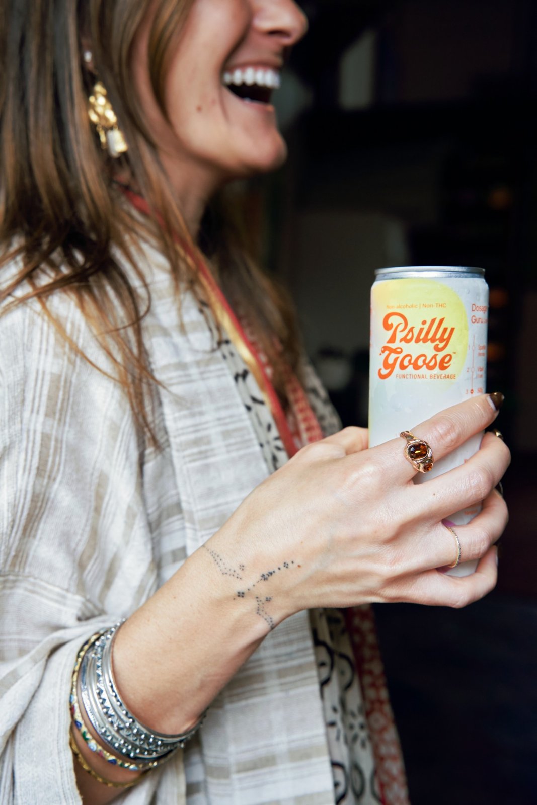 A woman laughing and holding a Psilly Goose functional beverage can