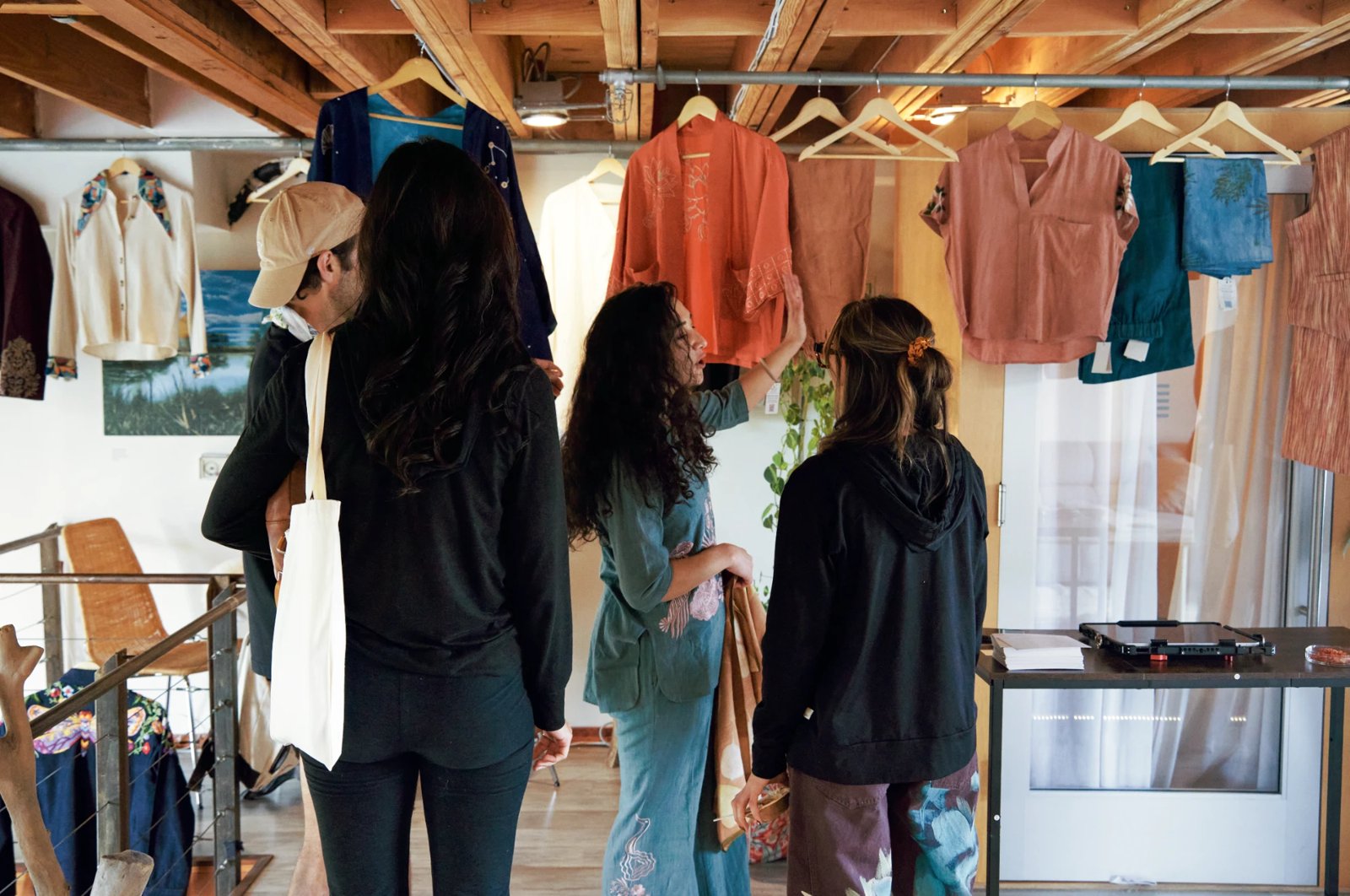 Guests browsing a rack of hand-dyed clothing hung from the wood ceiling beams