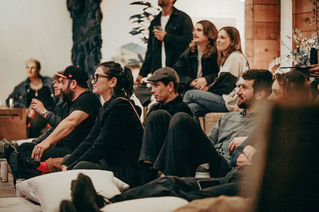Guests seated on the floor and on cushions listening to a performance