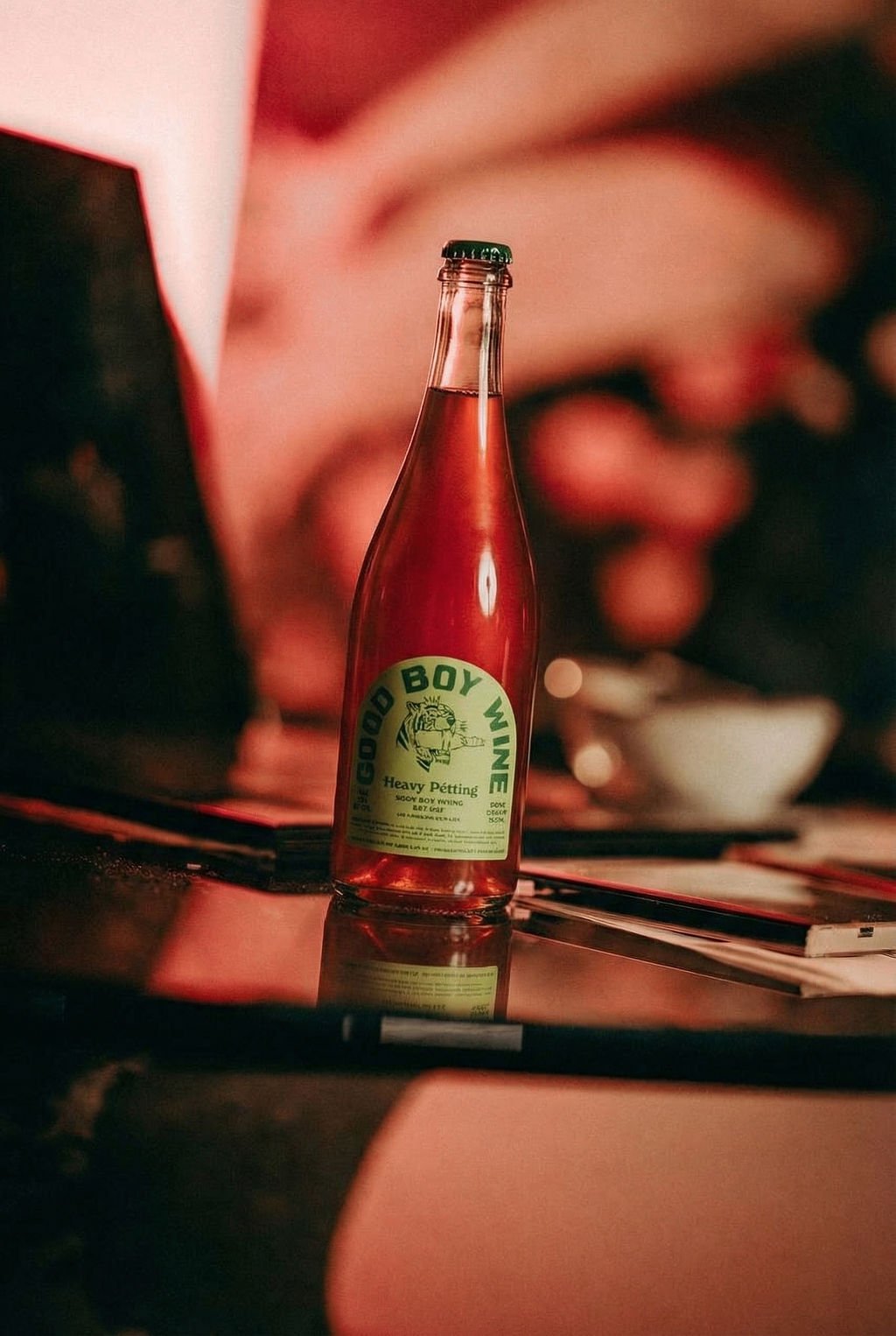 A bottle of Good Boy Wine Heavy Petting rose on a table in red light