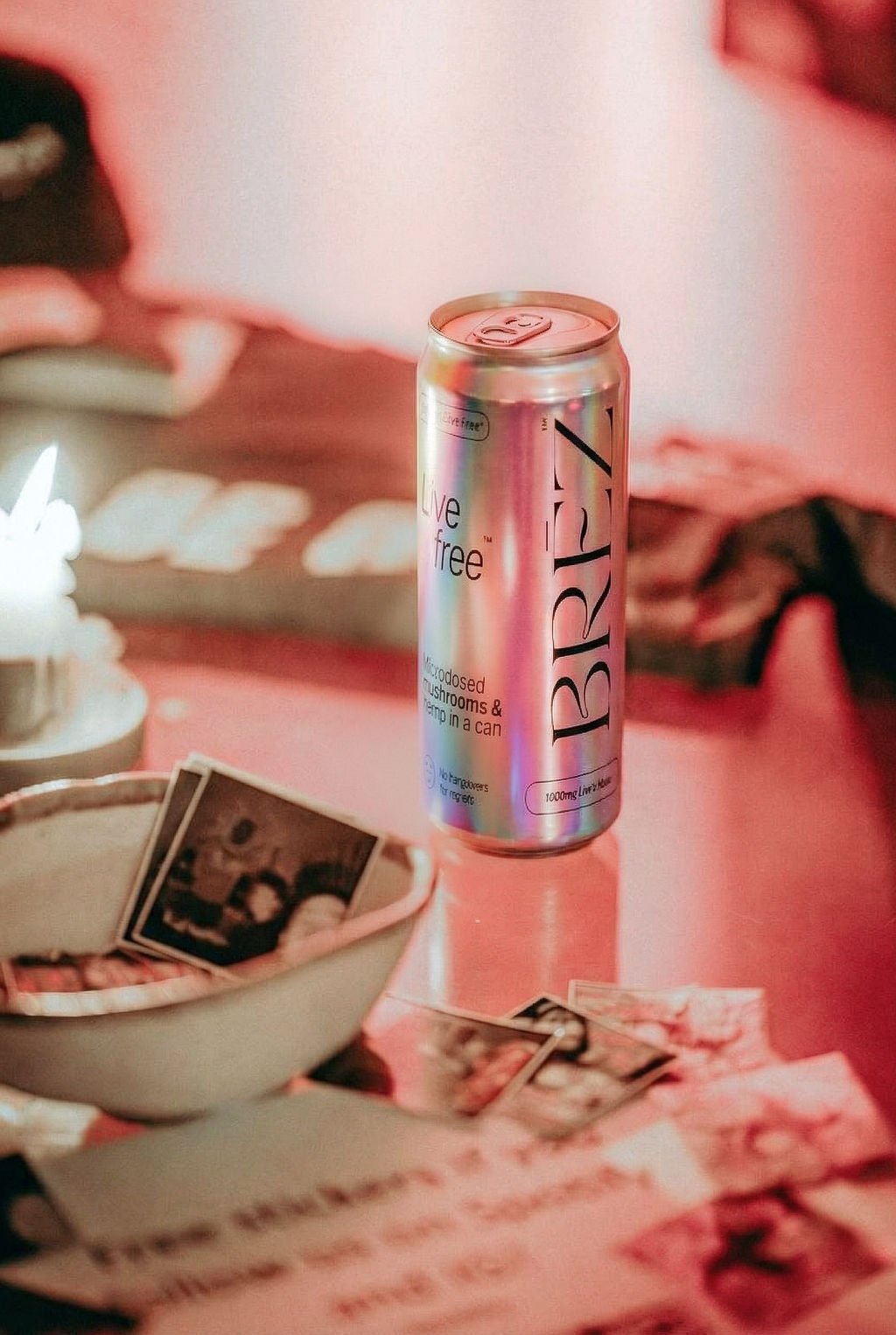 A BREZ can beside a candle and a bowl of instant photos