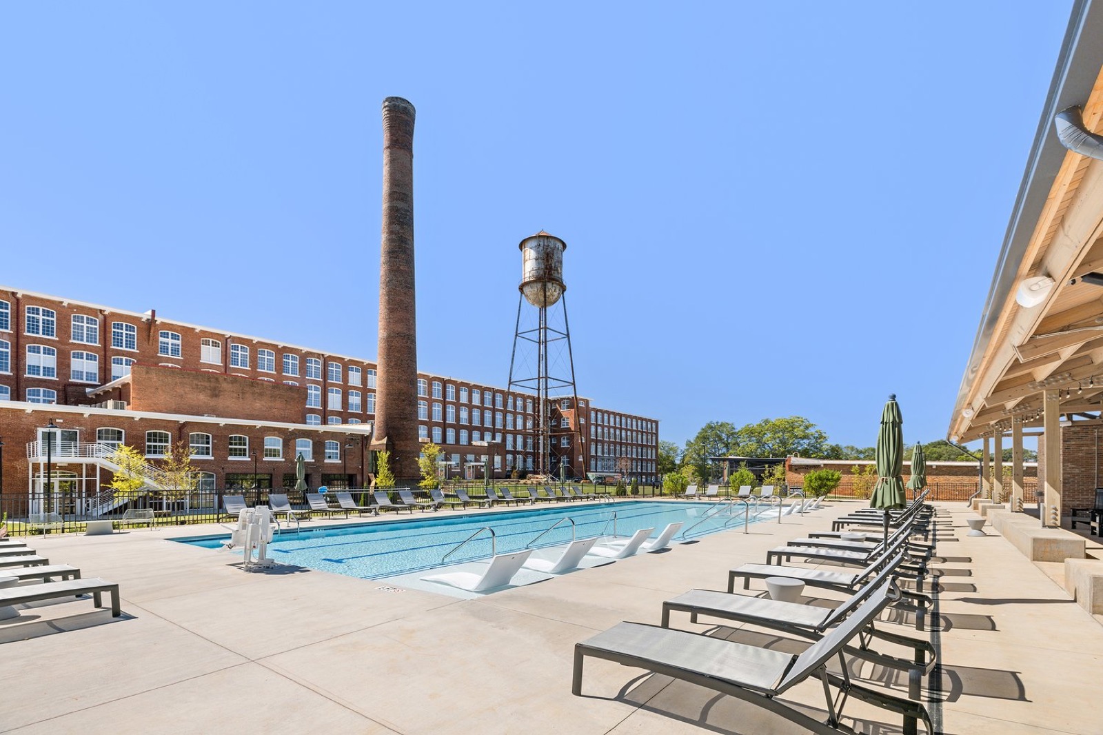 The pool with loungers, the brick smokestack, and the water tower in front of the mill