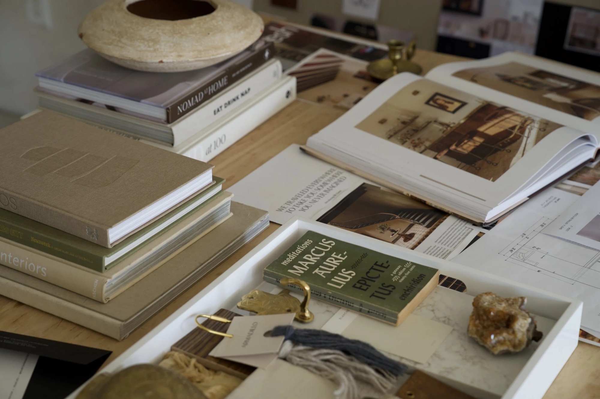 Design books, floor plans, fabric samples, and a tray of brass hardware and finish samples on a work table